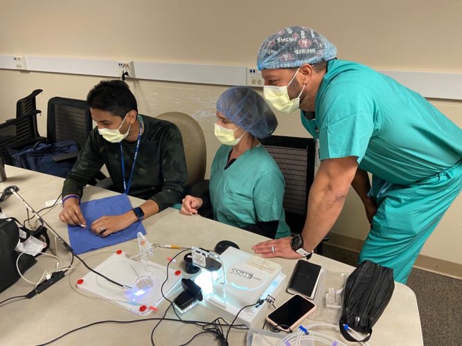ETOSS tech showing 2 participants how to use the device with a coronary guidewire