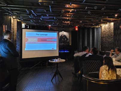presenter at a restaurant showing a powerpoint presentation projected on a large screen in front of participants at separate dinner tables