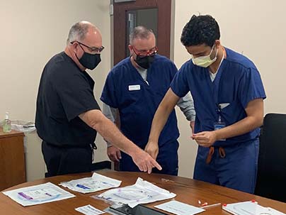 two AE live educators showing a participant different guidewires on an office table